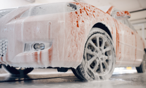 Przód czerwonego auta podczas używania aktywnej piany